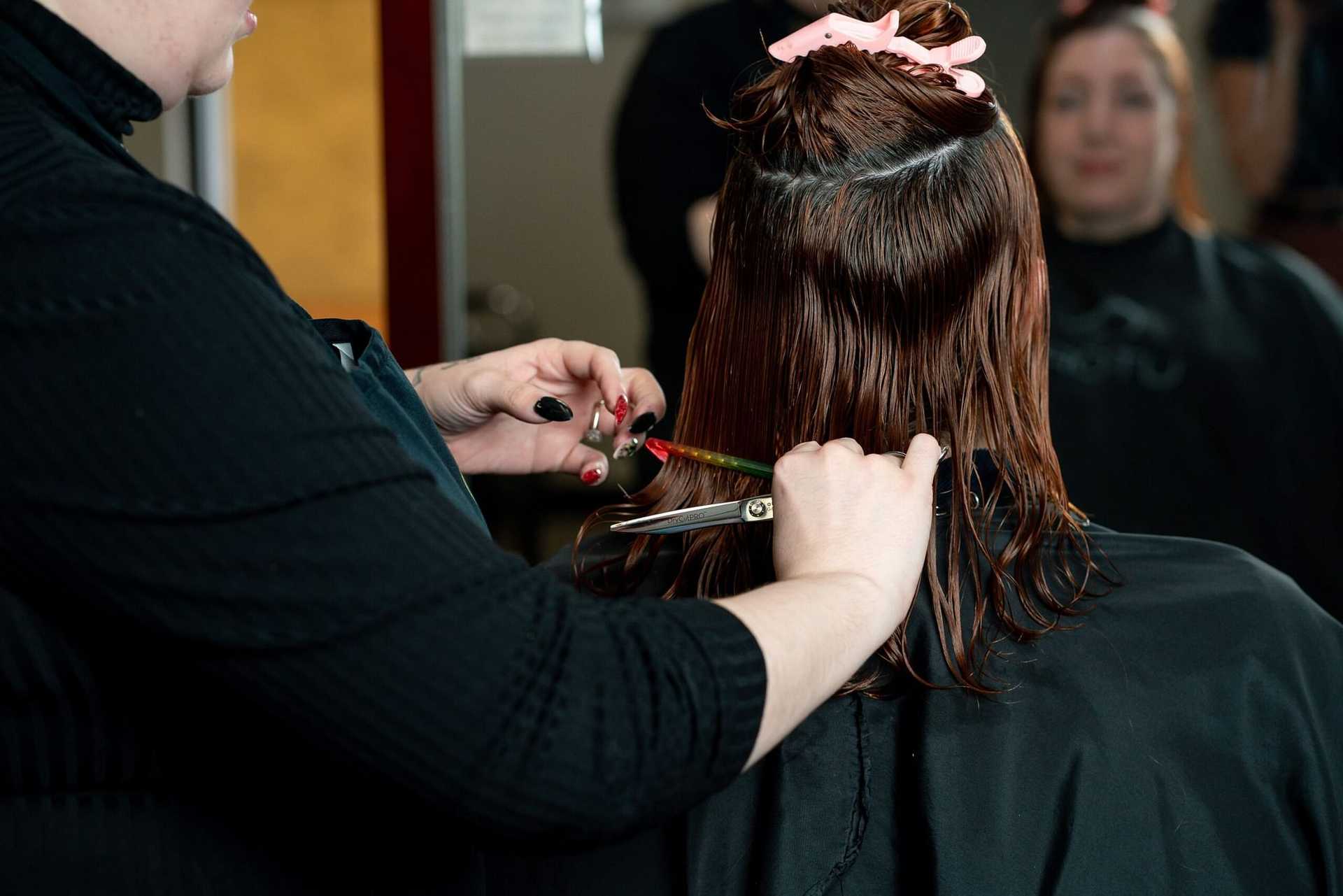 Stylist cutting a client's wet hair in a salon.